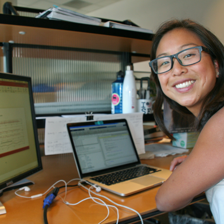 Photo of graduate student Johanna O'Day in the lab, coding on a computer with dual monitors.