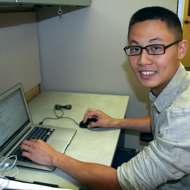 Photo of USRP student Alan Aw in his laboratory, working on a laptop computer.