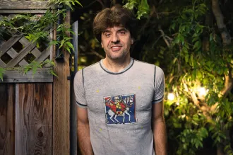Outdoor nighttime photo of Karl Deisseroth leaning against a wooden gate.