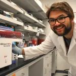 Indoor photo of a graduate student using a flow cytometer.