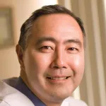 Indoor headshot photo of a smiling Asian male faculty member, Dr. Klete Kushida, Professor of Psychiatry & Behavioral Sciences at Stanford University.
