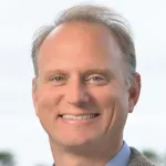 Outdoor headshot photo of a smiling white male faculty member, Dr. Mac Schwager, Associate Professor of Aeronautics and Astronautics at Stanford University.