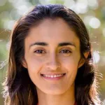 Outdoor headshot photo of a smiling female faculty member, Dr. Maya Mathur, Assistant Professor of Pediatrics and Medicine at Stanford University.