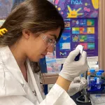 Indoor photo of a graduate student using a pipetter.