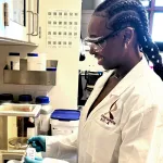 Indoor photo of a graduate student working at a lab bench.