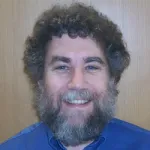 Indoor headshot photo of a smiling white male faculty member, Dr. Steven Block, Professor Emeritus of Applied Physics at Stanford University.