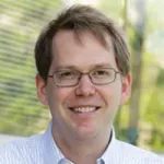 Outdoor headshot photo of a smiling white male faculty member, Dr. William Greenleaf, Professor of Genetics at Stanford University.