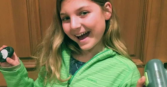 Photo of Jamie Kurtzig, 12-year-old girl with diabetes, holding some of her hybrid closed-loop system equipment.