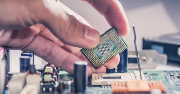 Photo showing a person's hand taking a computer chip out of a computer.