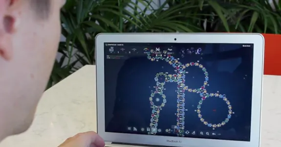 Screenshot of a student looking at the Eterna game on a laptop screen, with a folding protein depicted in bright colors.