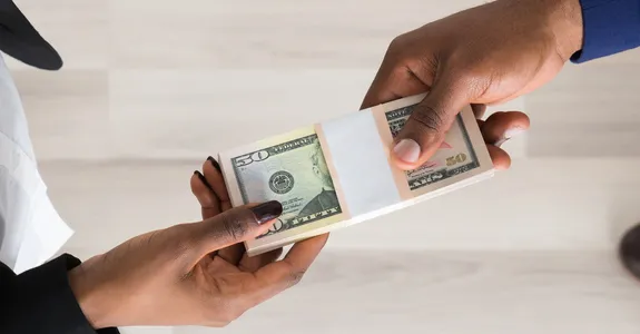 Photo from above of a man and a woman exchanging a stack of dollar bills.
