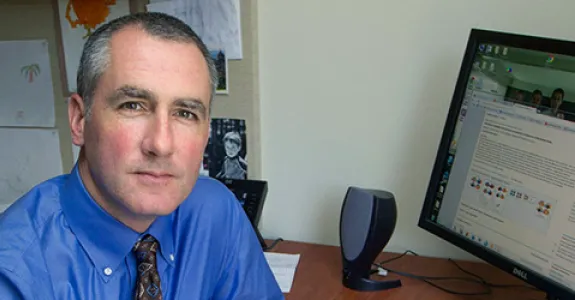 Photo of Dr. Michael Greicius in office, sitting in front of a computer.