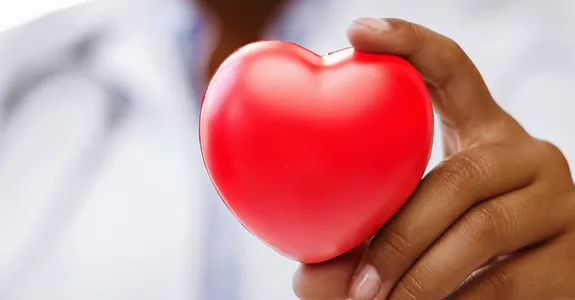 Photo of doctor holding up a toy heart.