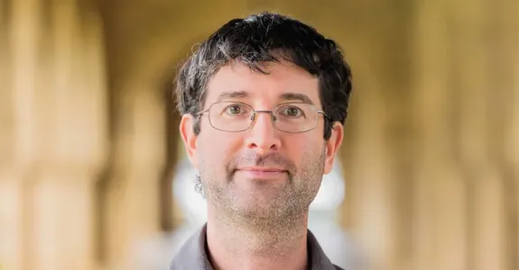 Photo of a white male faculty member in glasses standing in one of Stanford's arcades.