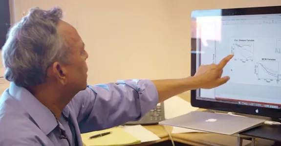 Screenshot of Dr. Shripad Tuljapurkar indicating graphs on computer screen.