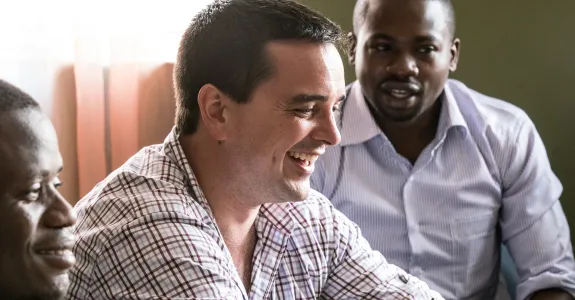 Photo of Dr. Mike Baiocchi laughing with two colleagues in Kenya.