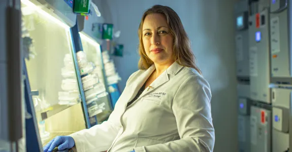 Photo of Dr. Michelle Monje seated in the laboratory, wearing a lab coat.