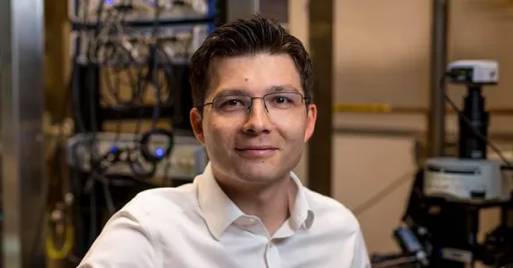 Indoor photo of a white male faculty member sitting in a wet laboratory and smiling at the camera.