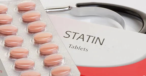 Photo of a packet of pink statin pills on top of a labeled box, with a stethoscope in the background.