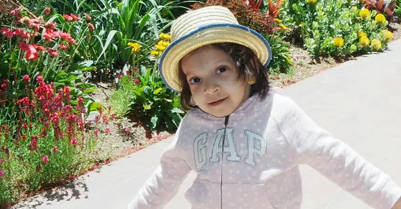 Photo of a little girl walking on a path wearing a hat.