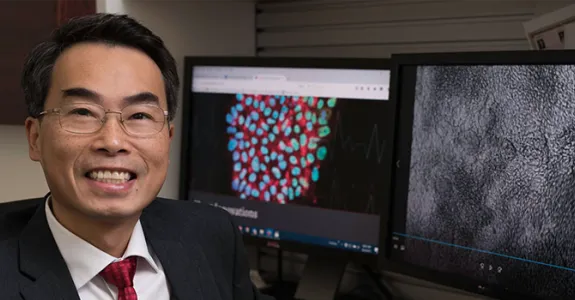 Photo of Dr. Joseph Wu sitting in front of computer screens.