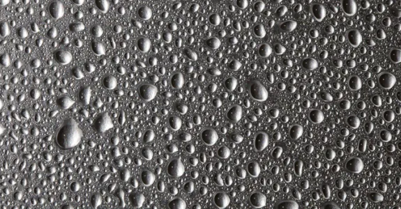 Image of water droplets of varying sizes on a gray background.