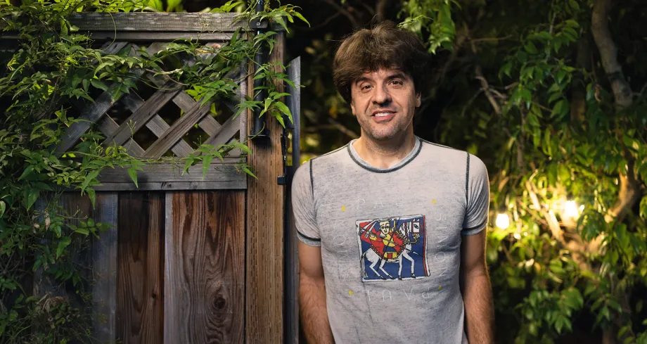Outdoor nighttime photo of Karl Deisseroth leaning against a wooden gate.