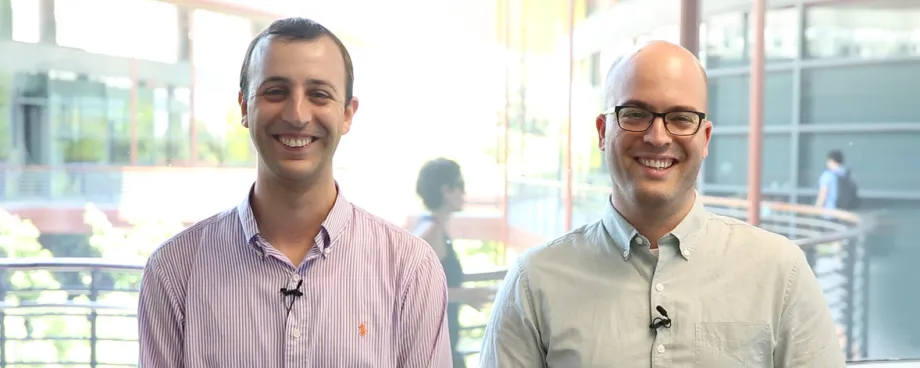 Indoor photo of Dr. Adam de la Zerda and Dr. Yonatan Winetraub, two adult white male faculty members at Stanford, standing side by side and smiling at the camera, one wearing glasses.