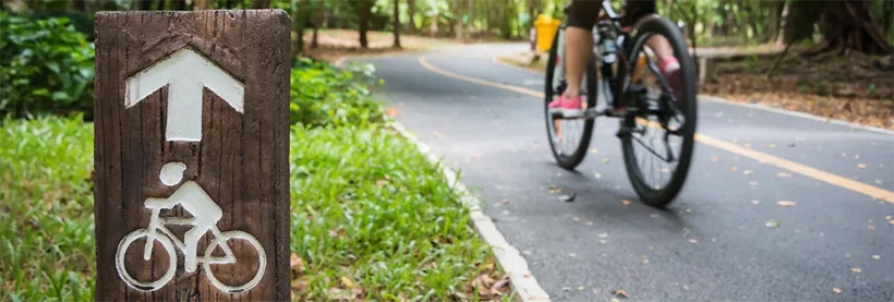 Photo of a person biking near a bike sign.