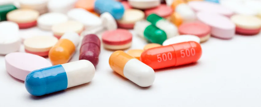 Photo of an assortment of colorful pills spilled across a white surface.