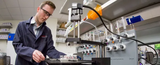 Photo of undergraduate student Zachary Rosenthal loading protein samples onto the crystallization robot at Macromolecular Structure Knowledge Center.