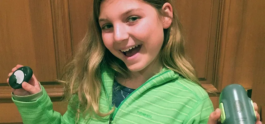 Photo of Jamie Kurtzig, 12-year-old girl with diabetes, holding some of her hybrid closed-loop system equipment.
