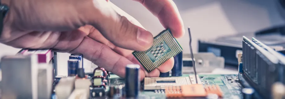 Photo showing a person's hand taking a computer chip out of a computer.