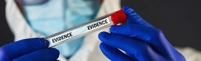 Photo of a man in hazard safety gear wearing blue gloves and holding up a vial labeled "evidence".