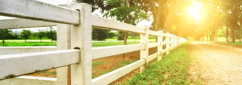 Photo of white fence going off into the distance along a path.