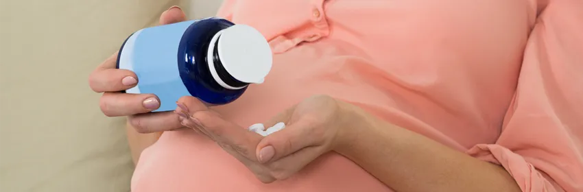 Photo of pregnant woman holding medicine bottle.
