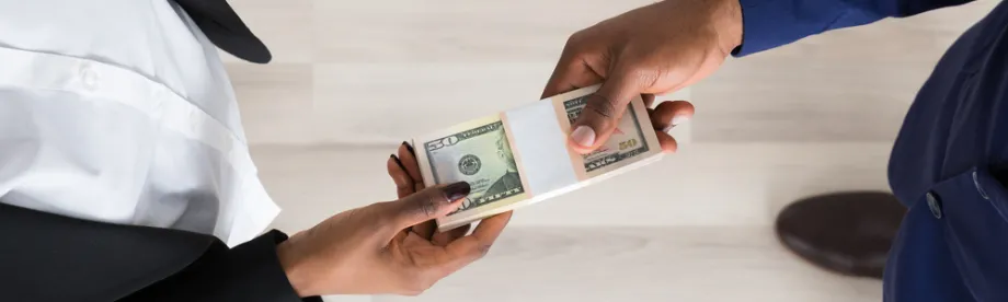 Photo from above of a man and a woman exchanging a stack of dollar bills.