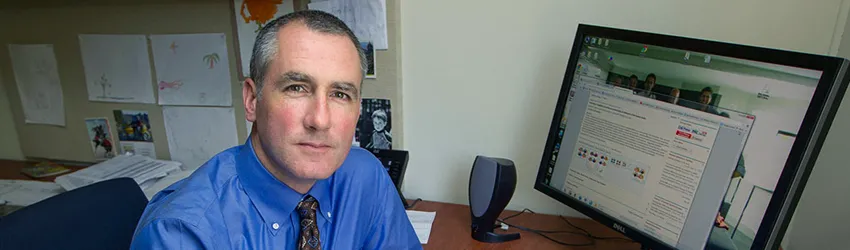 Photo of Dr. Michael Greicius in office, sitting in front of a computer.