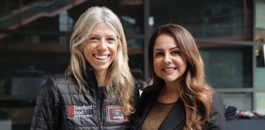 Photo of two women standing together outdoors, smiling at the camera.