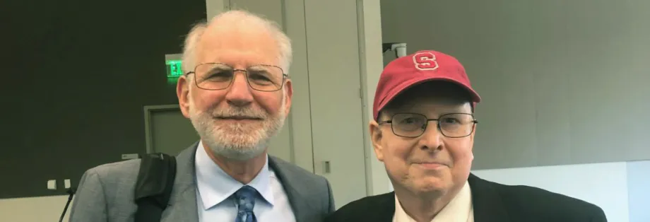 Photo of elder doctor and middle-aged man wearing a red hat.