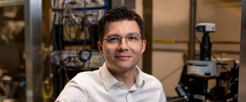 Indoor photo of a white male faculty member sitting in a wet laboratory and smiling at the camera.