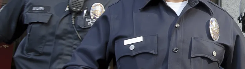 Photo of two police officers, showing the badges and name pins on their uniforms.