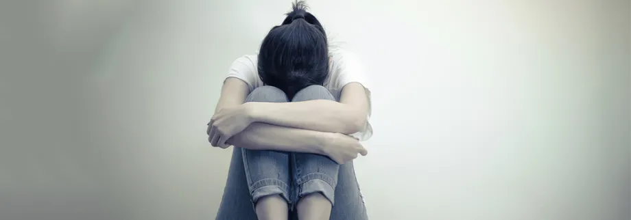 Photo of girl huddling against wall.