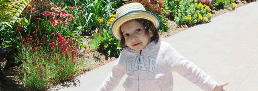 Photo of a little girl walking on a path wearing a hat.
