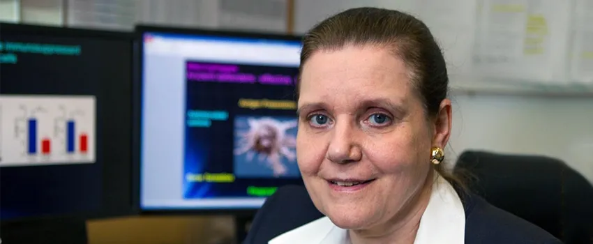 Photo of Dr. Connie Weyand in her office with computers in the background.