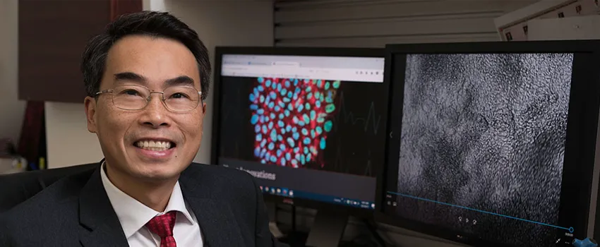 Photo of Dr. Joseph Wu sitting in front of computer screens.