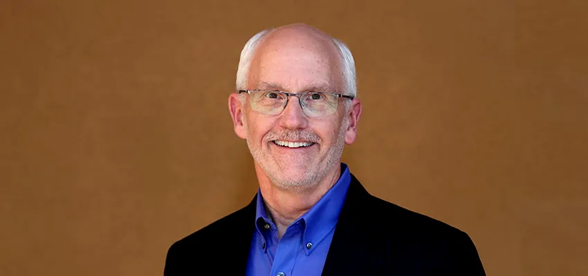 Photo of Dr. Paul Yock standing in front of a brown background.