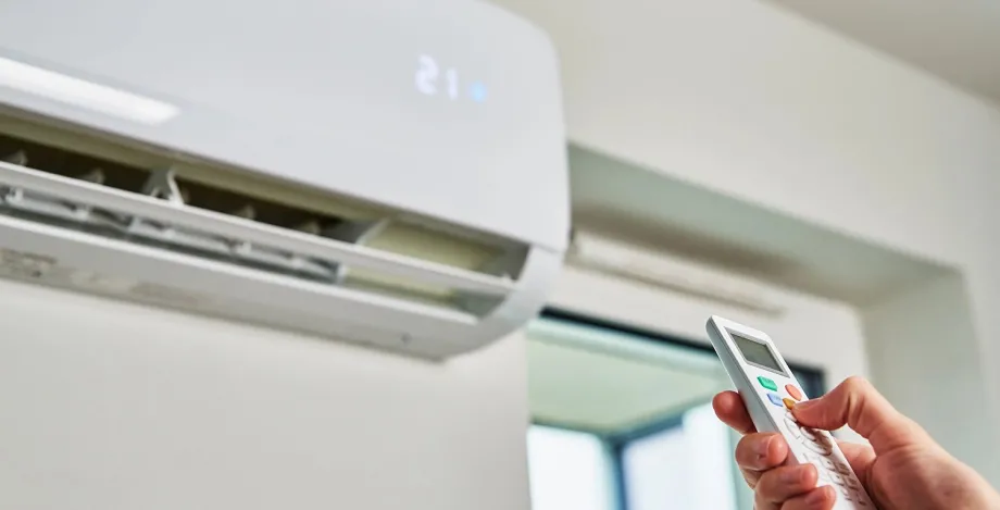 Photo of a person's hand holding a remote up towards a ventilation system.